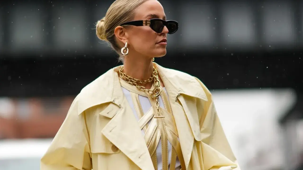 Stylische Frau mit Dutt, Sonnenbrille und auffälligem Schmuck. Eine perfekte Frisur, die auch bei fettigen Haaren gut aussieht.