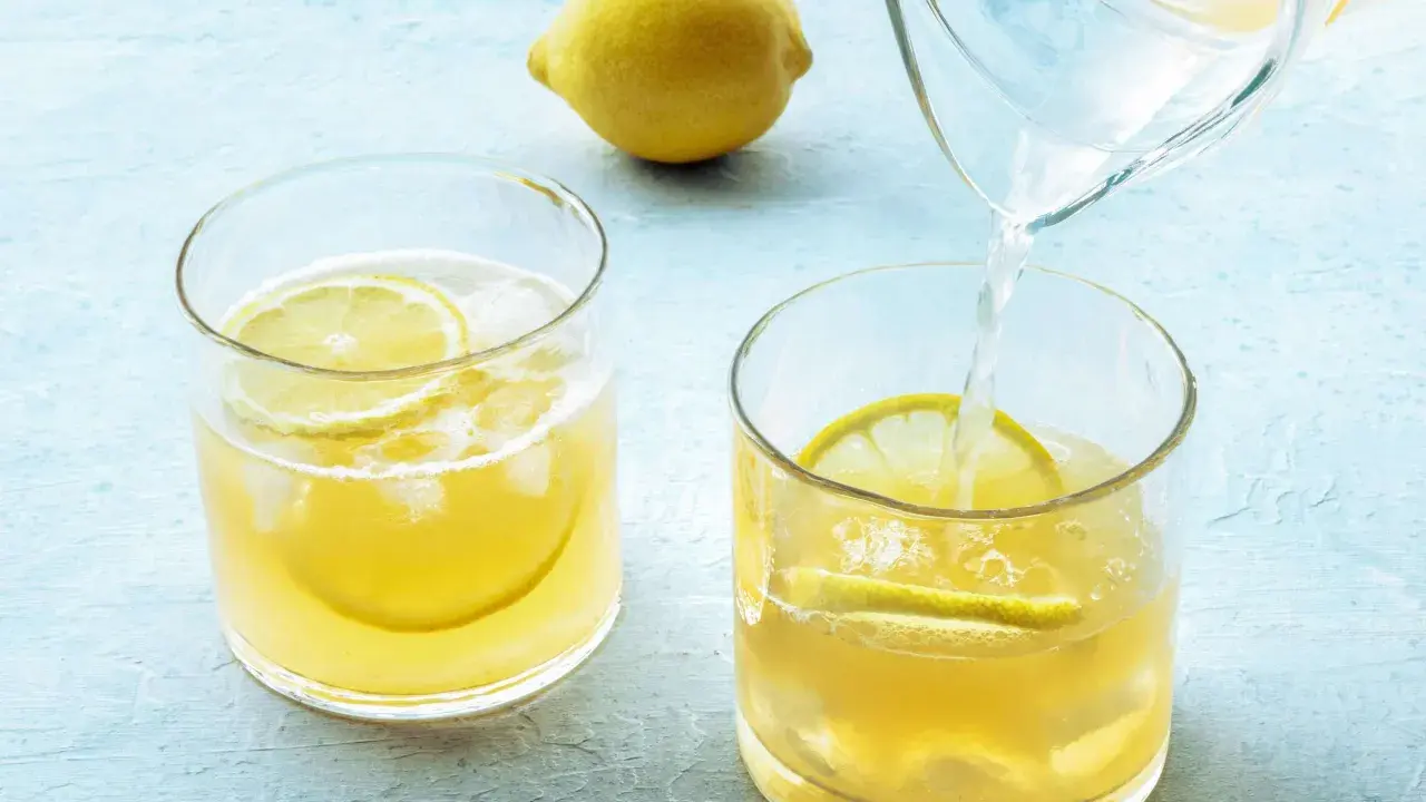 Erfrischendes zitronenwasser morgens wird in Gläser mit Eis und Zitronenscheiben gegossen.