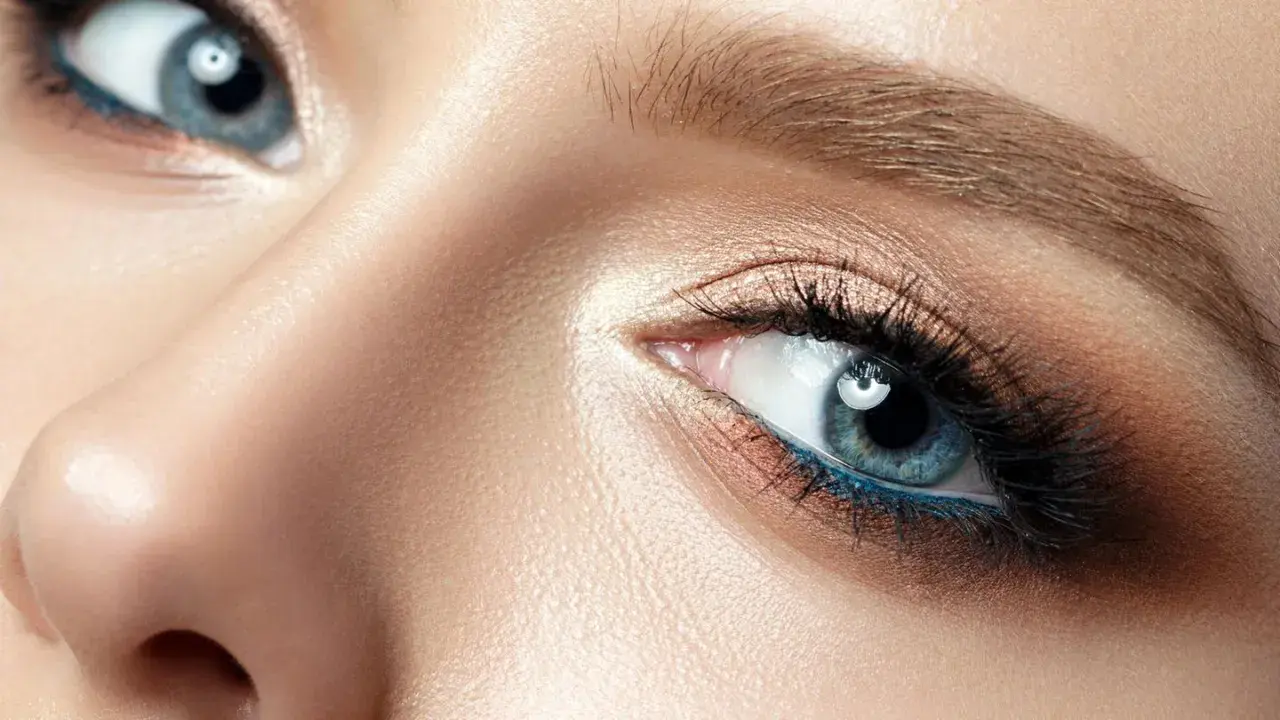 Nahaufnahme eines blauen Auges mit aufwendigem Augen-Make-up, das zeigt, wie man Augenlider schminkt.