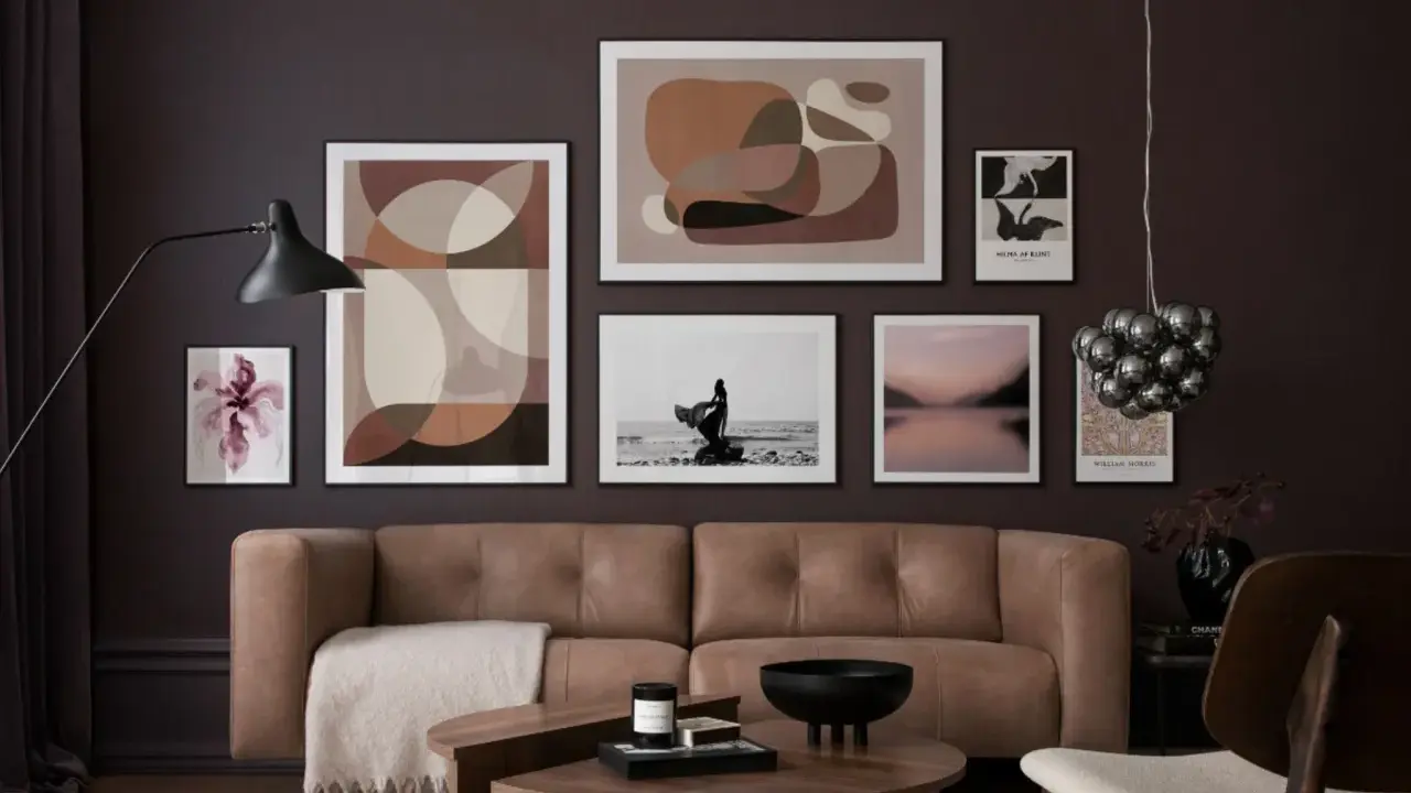 Ein Wohnzimmer mit brauner Ledercouch, Kunstwerken in Erdtönen und einem schwarzen Lampenschirm. Diese Farben passen gut zu Schwarz und schaffen eine elegante Atmosphäre.