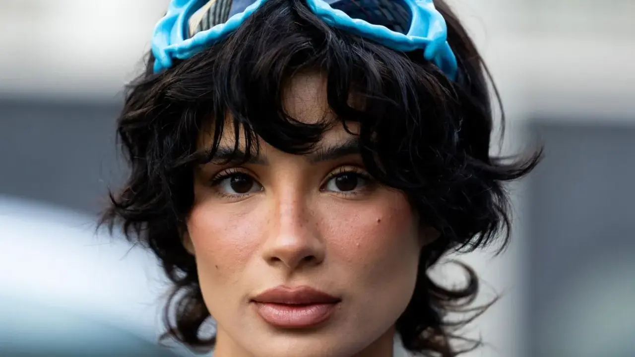 Ein Model mit einer shixie Frisur und blauen Skibrillen auf dem Kopf.