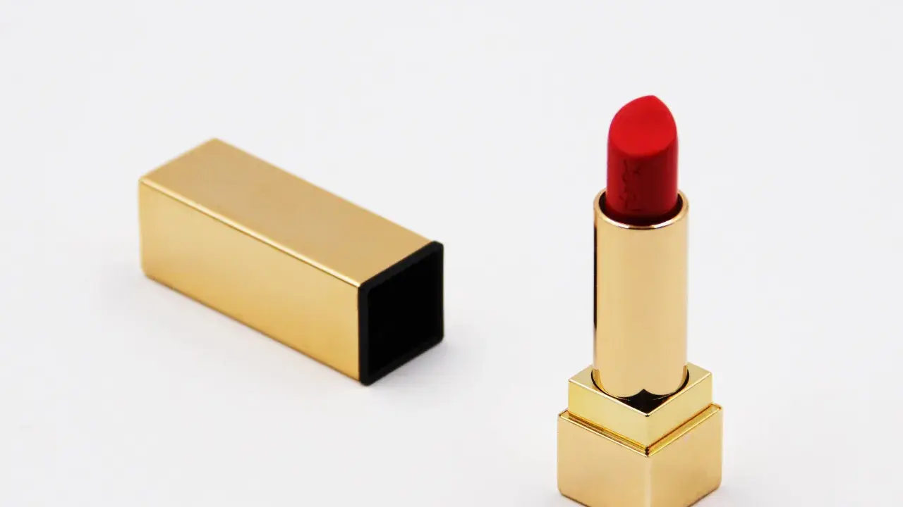 Ein roter Lippenstift in goldenem Etui, bereit für den perfekten Auftritt. Die Frage nach der Lippenstift Haltbarkeit ist hier nebensächlich, denn dieser Luxus ist zeitlos.