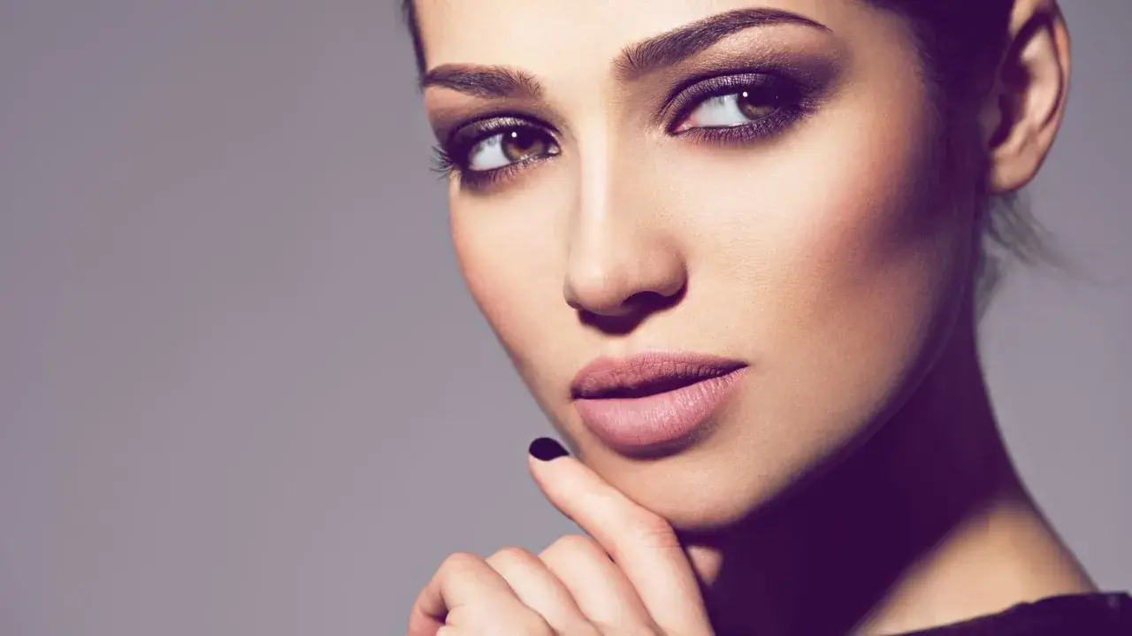 Ein Porträt einer Frau mit **smokey eyes dezent**. Ihre Augen sind von einem sanften, rauchigen Lidschatten umrahmt, der ihre braunen Augen betont.