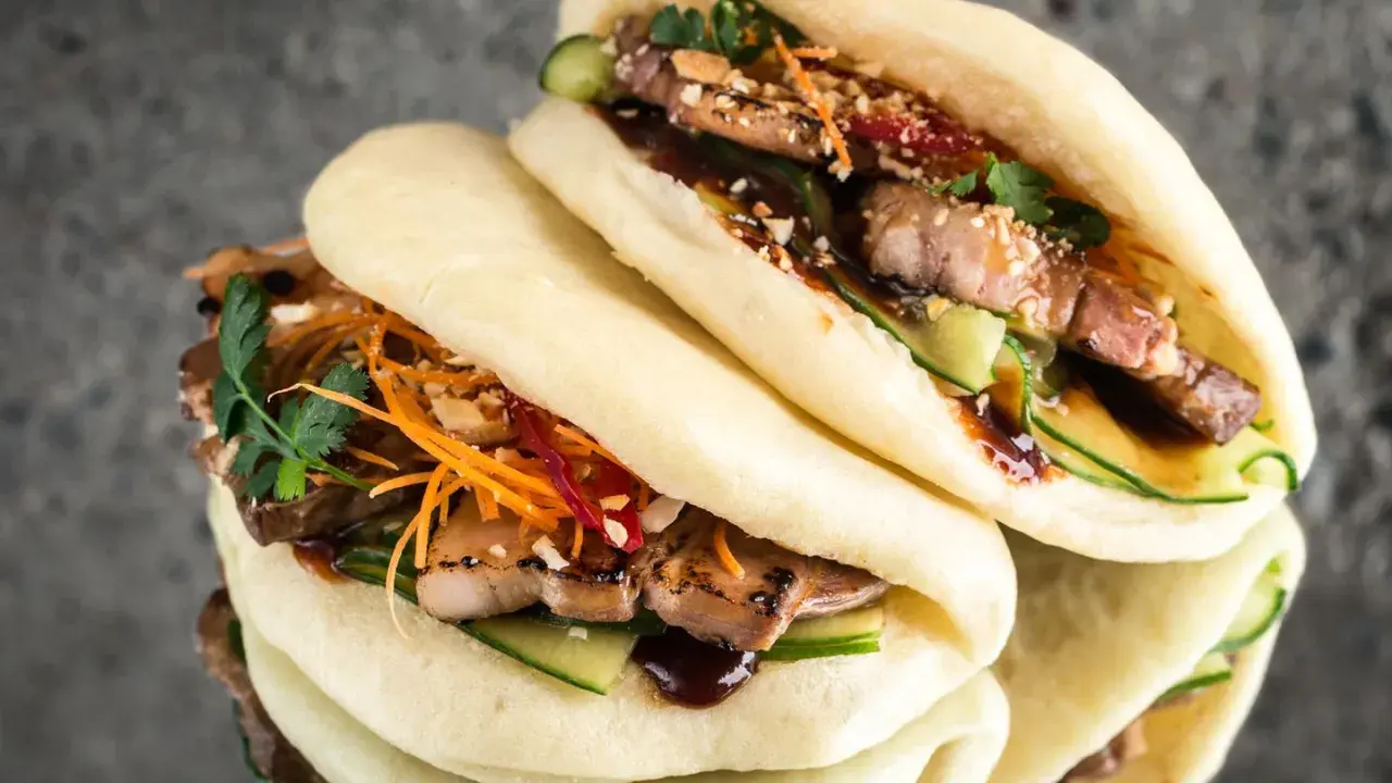 Saftige bao buns mit gegrilltem Fleisch, Gurke, Karottenstreifen und Koriander. Ein Genuss für alle Sinne!