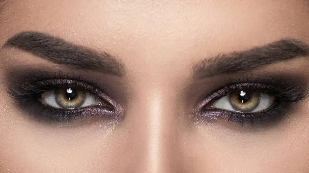 Nahaufnahme von Augen mit **stark geschminkten Augen**, dunklem Lidschatten und langen Wimpern.