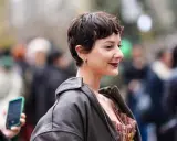 Frau mit einem langen Pixie-Haarschnitt, dunklem Lederjacke und auffälligem Kleid.