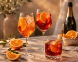 Erfrischende Aperol Spritz und Negroni Cocktails mit Orangenscheiben, Eis und einer Flasche Sekt – die perfekten spritz zutaten der iba.