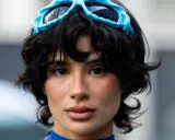 Ein Model mit einer shixie Frisur und blauen Skibrillen auf dem Kopf.