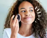 Frau mit Locken trägt Puder auf. Vorsicht, trocknet Babypuder die Haut aus?
