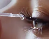 Ein Tropfen Serum auf einer Wimpernapplikator-Bürste, bereit, das Wachstum der Wimpern zu fördern.