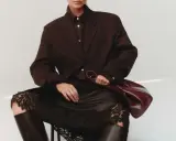 Elegant outfit: braun und schwarz kombinieren mit einem braunen Blazer, schwarzer Spitzenrock und Lederstiefel. Eine Hand hält eine weinrote Tasche.