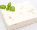 Ein Block Feta-Käse mit Basilikumblättern. Ist Feta gesund? Ja, er liefert Kalzium und Proteine.