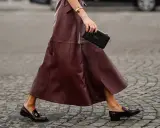 Schicke flache Schuhe zum Kleid: Dunkelrote Leder-Loafer mit goldenen Schnallen und ein passender Rock.