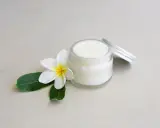 Creme in einem Glas mit einer Blüte und Blättern. Perfekt, um Deo selber machen mit Sheabutter.