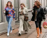 Drei Frauen spazieren mit Kaffee. Die mittlere trägt weite Hosen zu Pumps. Die rechte zeigt, welche Hose zu Boots Damen passt: Leggings und hohe Stiefel.