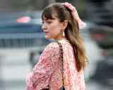 Eine Frau mit einem Blumenkleid und einer einfachen Frisur, perfekt für eine Hochzeitsgast. Ein Scrunchie mit Blumenmuster ziert ihren Pferdeschwanz.