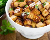 Knusprig gebratene Tofuwürfel in einer weißen Schüssel. Sie sehen lecker aus und man fragt sich, wie schmeckt tofu, wenn er so zubereitet wird.