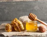 Honigwaben und ein Glas Honig mit einem Honigtaucher. Perfekt für eine natürliche Honig Zimt Maske.