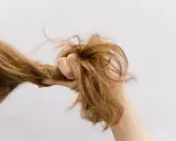 Eine Hand greift nach strohigen Haaren, die trocken und ungepflegt aussehen.