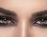 Nahaufnahme von Augen mit **stark geschminkten Augen**, dunklem Lidschatten und langen Wimpern.