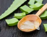 Frische Aloe Vera Stücke und Gel auf einem Holzlöffel. Perfekt für die Haarpflege.