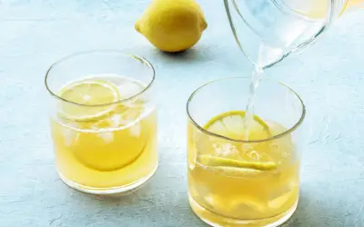 Erfrischendes zitronenwasser morgens wird in Gläser mit Eis und Zitronenscheiben gegossen.