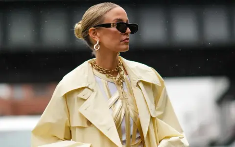 Stylische Frau mit Dutt, Sonnenbrille und auffälligem Schmuck. Eine perfekte Frisur, die auch bei fettigen Haaren gut aussieht.