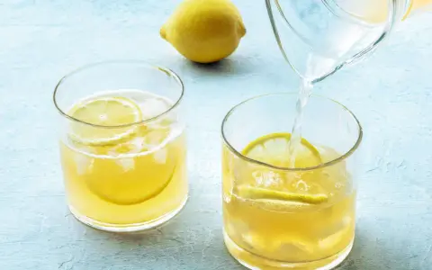Erfrischendes zitronenwasser morgens wird in Gläser mit Eis und Zitronenscheiben gegossen.