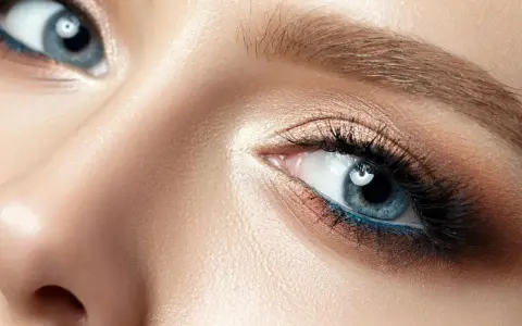 Nahaufnahme eines blauen Auges mit aufwendigem Augen-Make-up, das zeigt, wie man Augenlider schminkt.