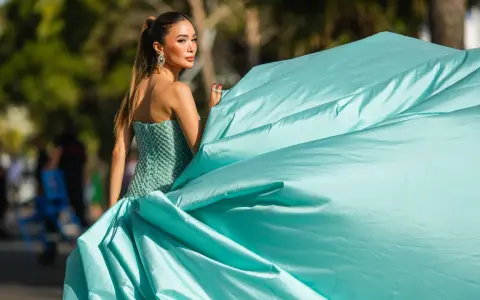Elegante Frau in einem mintgrünen, bestickten Kleid mit weitem Rock, bereit für einen Anlass, bei dem "black tie optional" gilt.