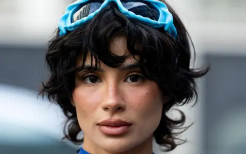 Ein Model mit einer shixie Frisur und blauen Skibrillen auf dem Kopf.