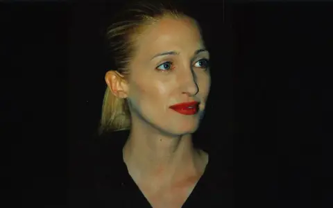 Frau mit blondem Pferdeschwanz und rotem Lippenstift, im **Carolyn Bessette-Kennedy Style**, blickt nach rechts.