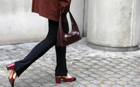 Schwarze Stoffhose kombinieren: Ein schicker Look mit brauner Tasche und zweifarbigen Slingback-Schuhen.