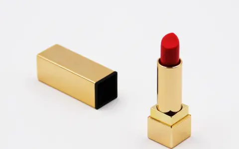 Ein roter Lippenstift in goldenem Etui, bereit für den perfekten Auftritt. Die Frage nach der Lippenstift Haltbarkeit ist hier nebensächlich, denn dieser Luxus ist zeitlos.