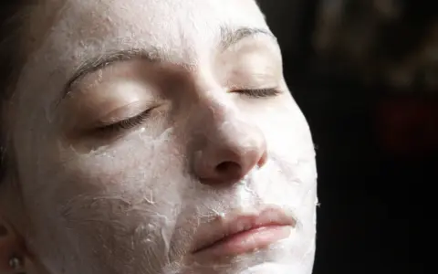 Nahaufnahme einer Frau mit geschlossenen Augen, die eine Quark Honig-Maske gegen Falten trägt.