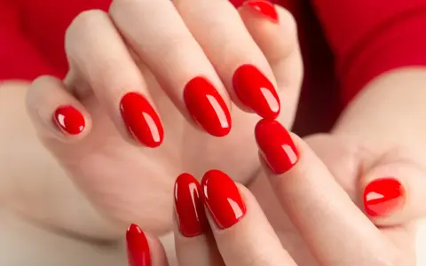 Hände mit leuchtend roten Nägeln, die die "red nail theory" verkörpern. Die glänzende Maniküre strahlt Selbstbewusstsein aus.