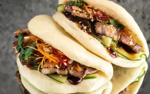 Saftige bao buns mit gegrilltem Fleisch, Gurke, Karottenstreifen und Koriander. Ein Genuss für alle Sinne!