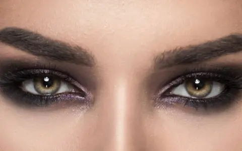 Nahaufnahme von Augen mit **stark geschminkten Augen**, dunklem Lidschatten und langen Wimpern.