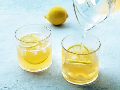 Erfrischendes zitronenwasser morgens wird in Gläser mit Eis und Zitronenscheiben gegossen.