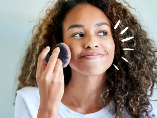 Frau mit Locken trägt Puder auf. Vorsicht, trocknet Babypuder die Haut aus?