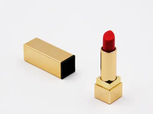 Ein roter Lippenstift in goldenem Etui, bereit für den perfekten Auftritt. Die Frage nach der Lippenstift Haltbarkeit ist hier nebensächlich, denn dieser Luxus ist zeitlos.