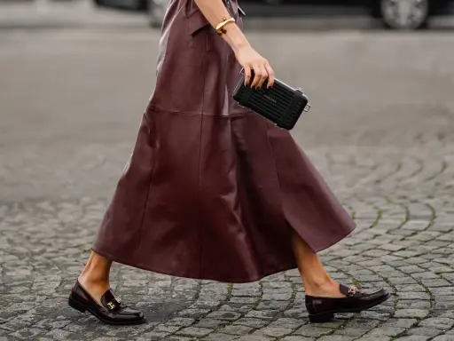 Schicke flache Schuhe zum Kleid: Dunkelrote Leder-Loafer mit goldenen Schnallen und ein passender Rock.