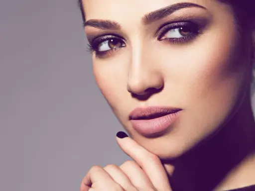 Ein Porträt einer Frau mit **smokey eyes dezent**. Ihre Augen sind von einem sanften, rauchigen Lidschatten umrahmt, der ihre braunen Augen betont.