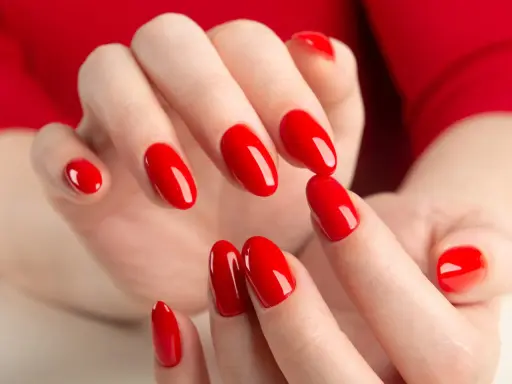 Hände mit leuchtend roten Nägeln, die die "red nail theory" verkörpern. Die glänzende Maniküre strahlt Selbstbewusstsein aus.