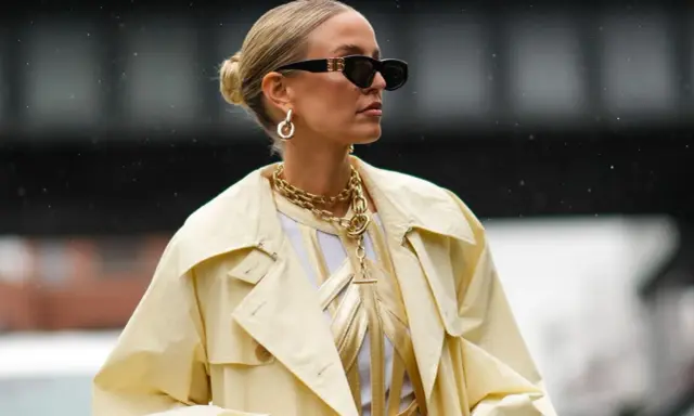 Stylische Frau mit Dutt, Sonnenbrille und auffälligem Schmuck. Eine perfekte Frisur, die auch bei fettigen Haaren gut aussieht.