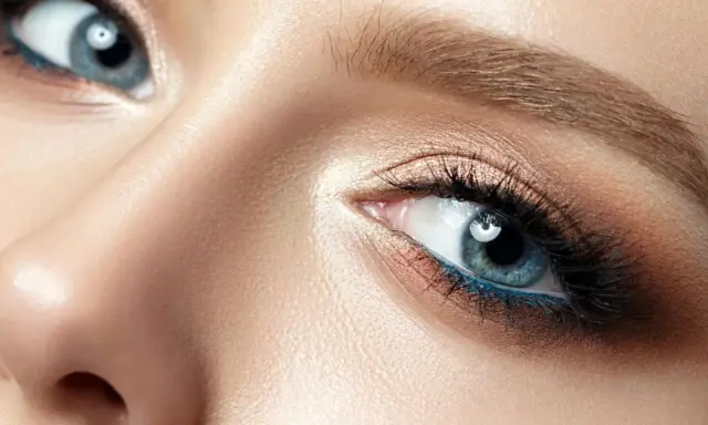 Nahaufnahme eines blauen Auges mit aufwendigem Augen-Make-up, das zeigt, wie man Augenlider schminkt.