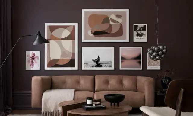 Ein Wohnzimmer mit brauner Ledercouch, Kunstwerken in Erdtönen und einem schwarzen Lampenschirm. Diese Farben passen gut zu Schwarz und schaffen eine elegante Atmosphäre.