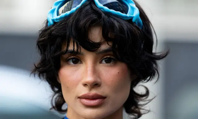 Ein Model mit einer shixie Frisur und blauen Skibrillen auf dem Kopf.