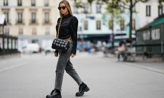 Stilvolle Frau in grauer Jeans, schwarzer Bluse und Plateau-Schuhen. Perfekt, um graue Jeans zu kombinieren!