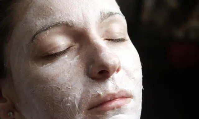 Nahaufnahme einer Frau mit geschlossenen Augen, die eine Quark Honig-Maske gegen Falten trägt.